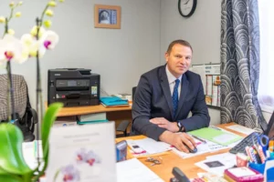 Conseiller funéraire assis à son bureau de travail, souriant face à l'objectif.