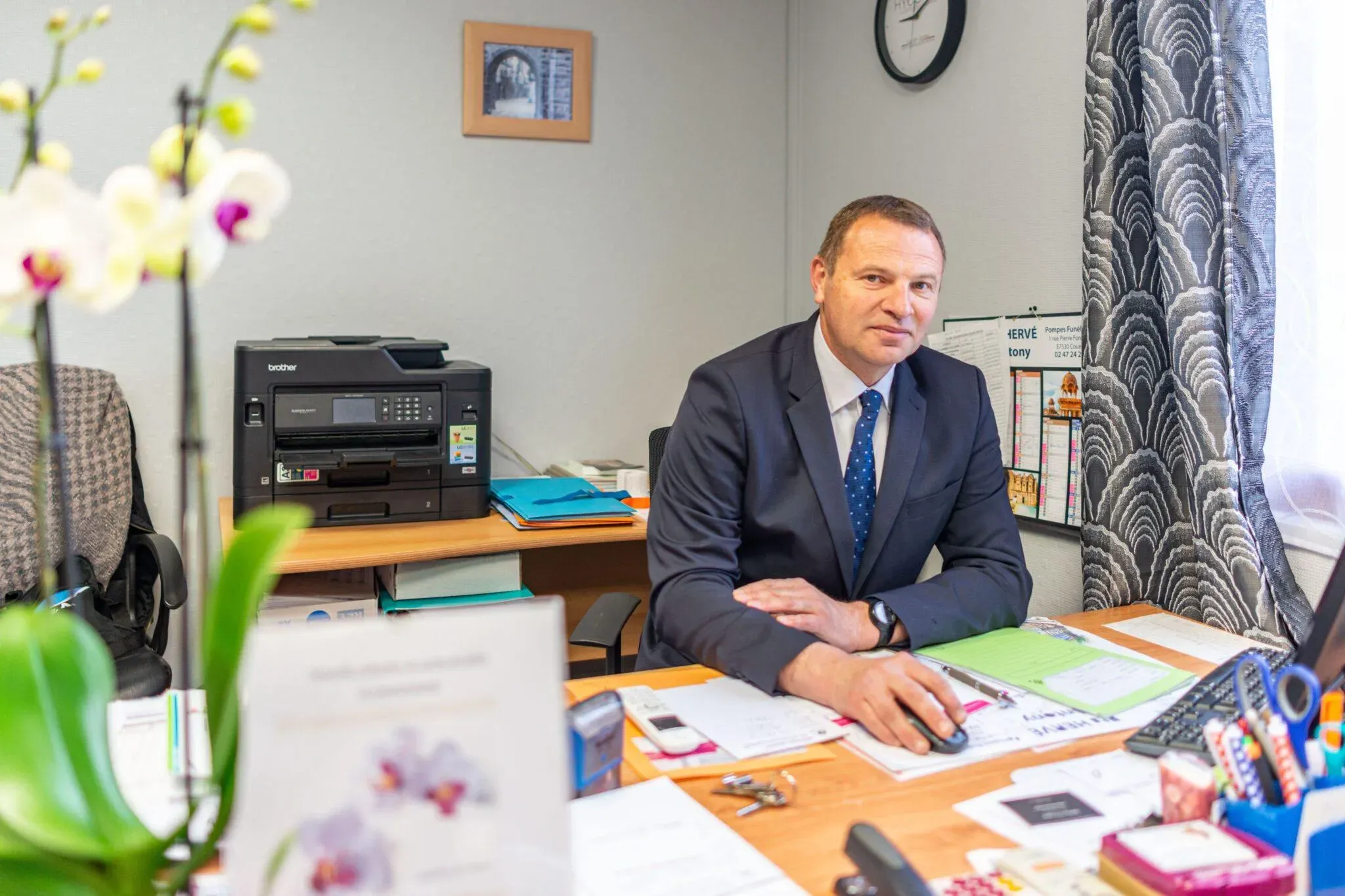 Conseiller funéraire assis à son bureau de travail, souriant face à l'objectif.