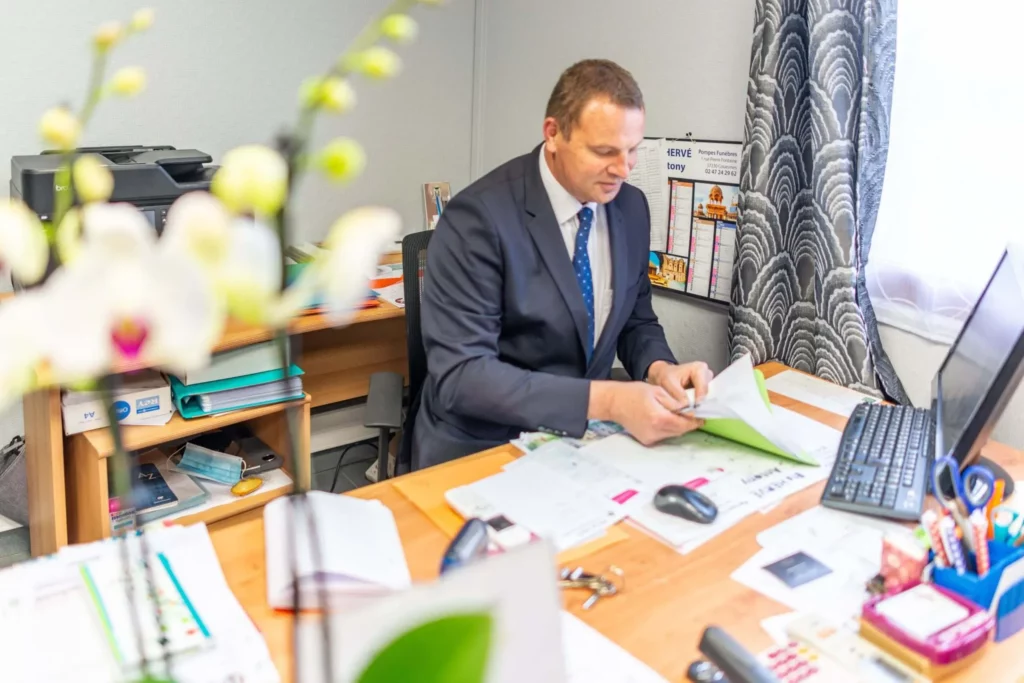 Un conseiller funéraire en costume travaille sur des dossiers à son bureau.