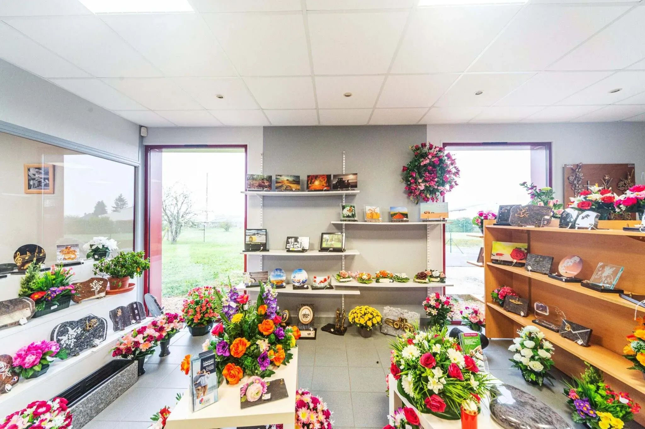 Vue d'ensemble d'une boutique funéraire présentant compositions florales et plaques du souvenir.